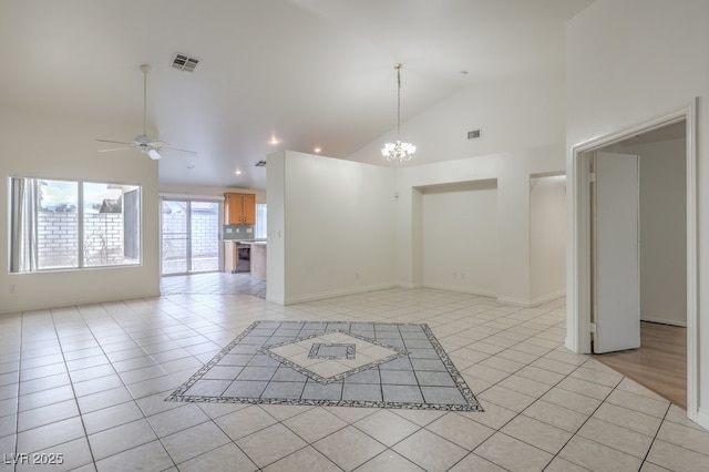 empty room featuring light tile patterned flooring, ceiling fan with notable chandelier, and high vaulted ceiling