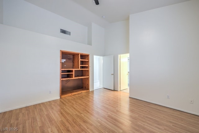 empty room with high vaulted ceiling and light hardwood / wood-style floors