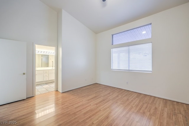 spare room with high vaulted ceiling and light wood-type flooring