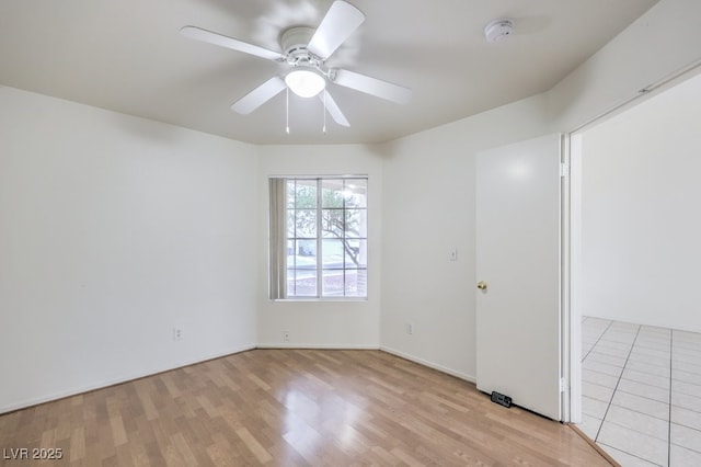 empty room with ceiling fan and light hardwood / wood-style flooring