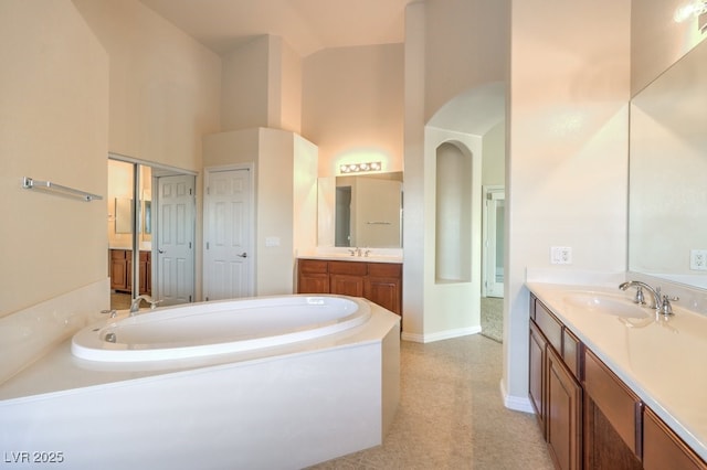 bathroom featuring vanity, a tub to relax in, and a towering ceiling