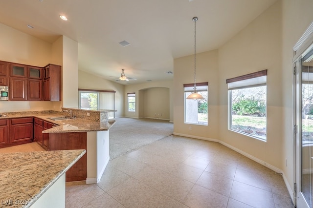 kitchen with pendant lighting, sink, high vaulted ceiling, light stone counters, and kitchen peninsula