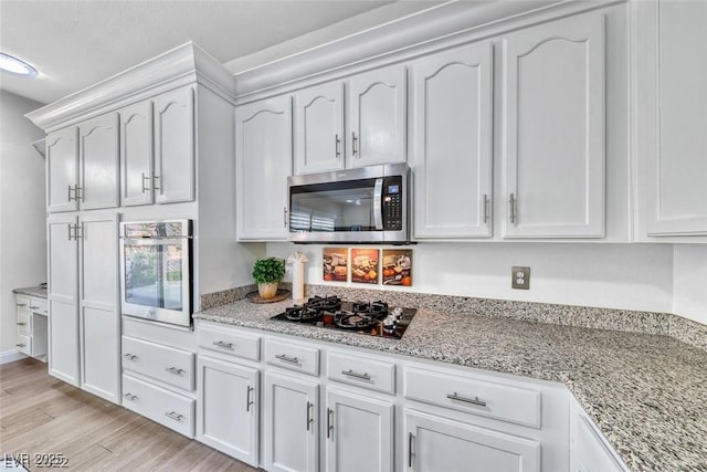 kitchen featuring light stone counters, appliances with stainless steel finishes, and white cabinets