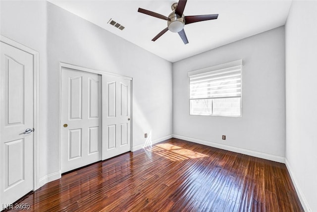 unfurnished bedroom with dark wood-type flooring, ceiling fan, and a closet