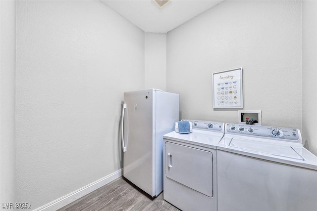 laundry area featuring washing machine and dryer and light hardwood / wood-style floors