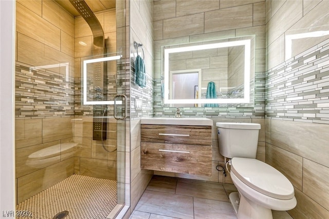 bathroom with toilet, vanity, tile patterned floors, and a shower with shower door