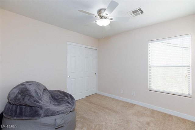 sitting room with ceiling fan and light colored carpet