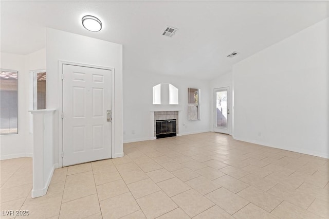 unfurnished living room with light tile patterned floors, vaulted ceiling, and a tile fireplace