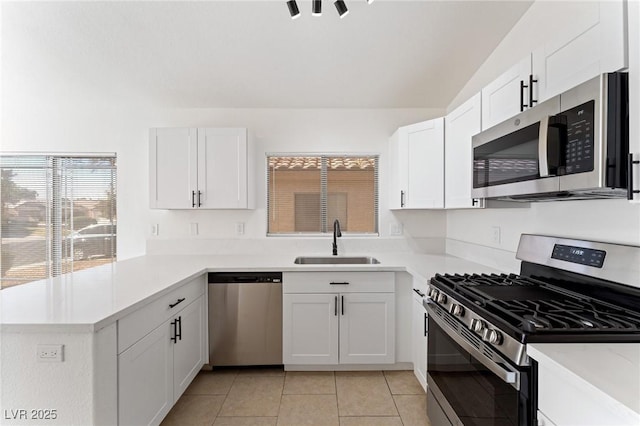 kitchen with appliances with stainless steel finishes, kitchen peninsula, sink, and white cabinets