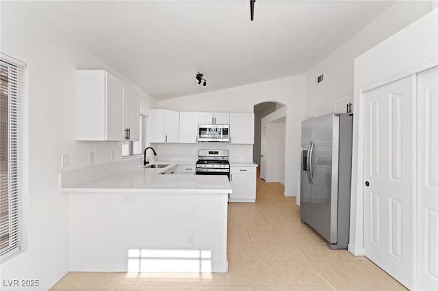 kitchen with sink, vaulted ceiling, kitchen peninsula, stainless steel appliances, and white cabinets