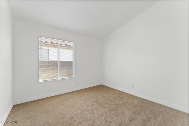 empty room featuring light colored carpet and vaulted ceiling