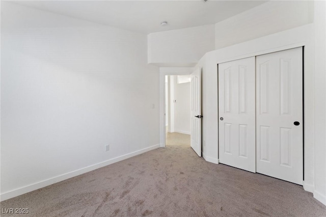 unfurnished bedroom featuring light colored carpet and a closet