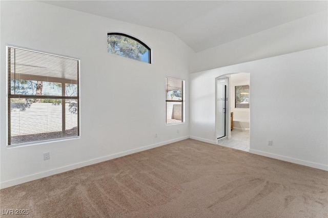 carpeted empty room with vaulted ceiling