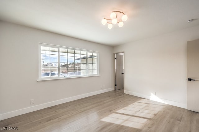 spare room featuring light hardwood / wood-style flooring and a chandelier