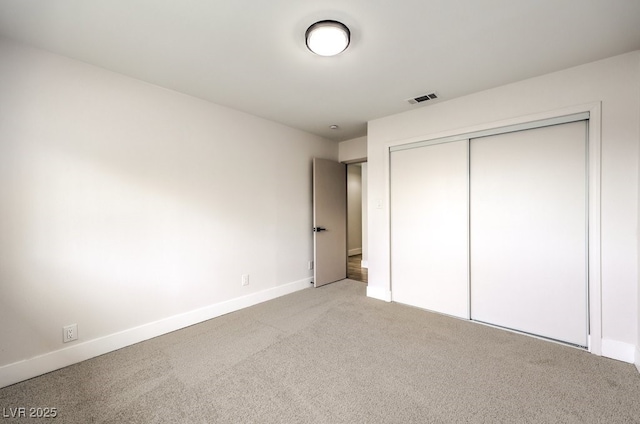 unfurnished bedroom with light colored carpet and a closet