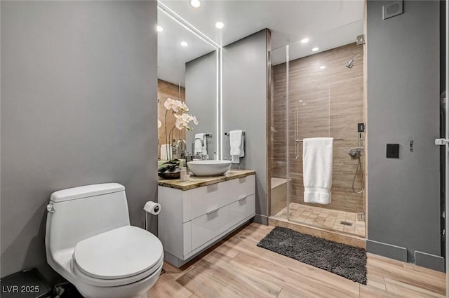 bathroom featuring hardwood / wood-style flooring, vanity, toilet, and a shower with door