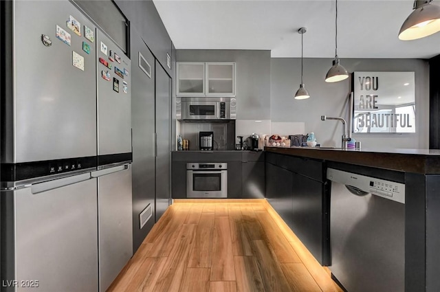 kitchen with sink, decorative light fixtures, stainless steel appliances, and light hardwood / wood-style floors