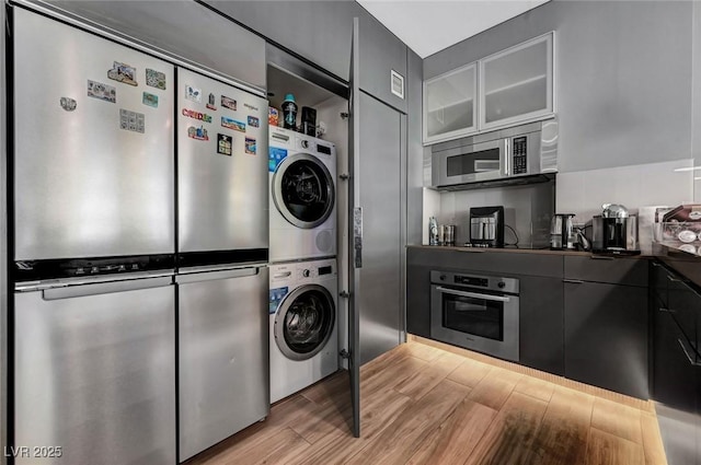 laundry area with stacked washer and dryer and light wood-type flooring