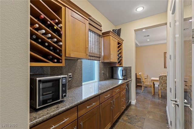 kitchen with dark stone countertops, backsplash, and crown molding