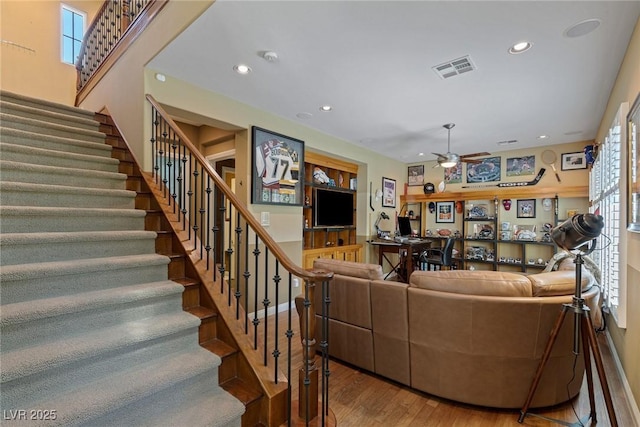 living room featuring hardwood / wood-style flooring, ceiling fan, and built in features