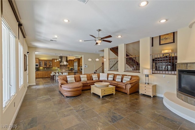 living room featuring ceiling fan, a tile fireplace, and a wealth of natural light