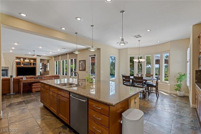 kitchen featuring pendant lighting, sink, a kitchen island with sink, light stone countertops, and stainless steel dishwasher