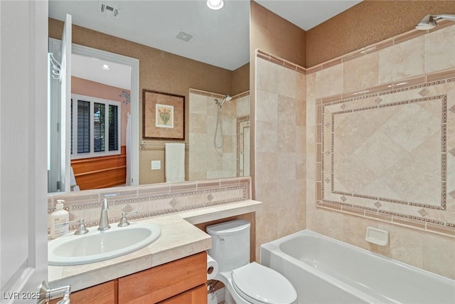 full bathroom featuring tile walls, backsplash, tiled shower / bath combo, vanity, and toilet