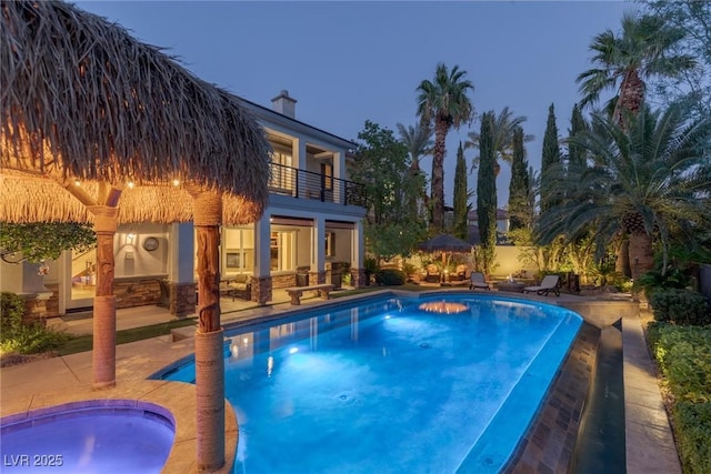 pool at dusk with a jacuzzi and a patio