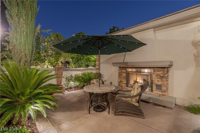 patio at twilight featuring an outdoor stone fireplace