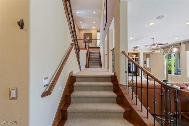 stairway featuring ceiling fan