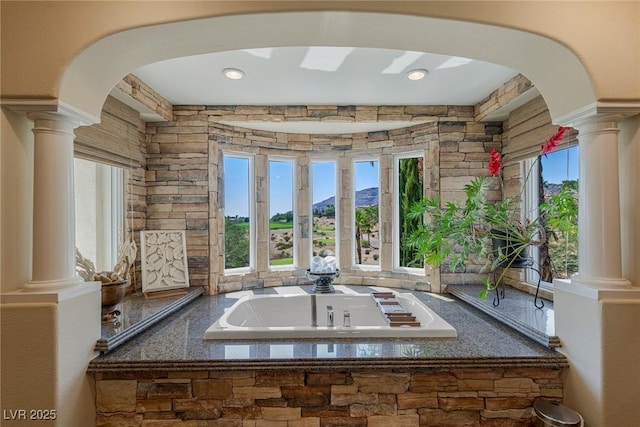 bathroom with decorative columns and a tub