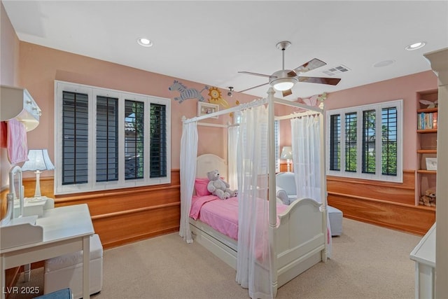 carpeted bedroom featuring wooden walls and ceiling fan