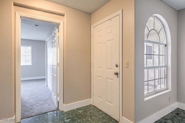 foyer with dark tile patterned flooring and a textured ceiling