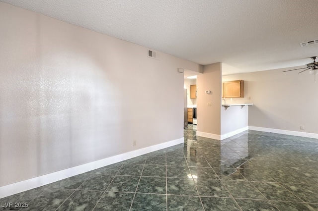 empty room featuring a textured ceiling and ceiling fan