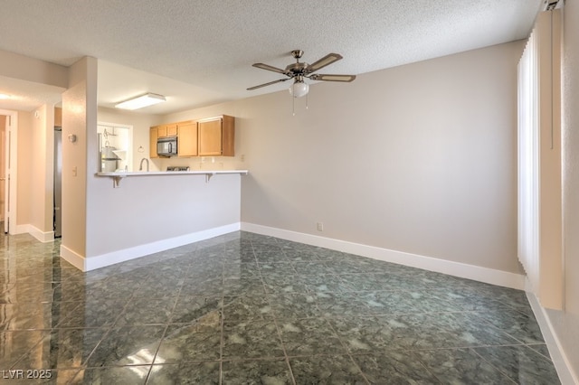 unfurnished living room with ceiling fan and a textured ceiling