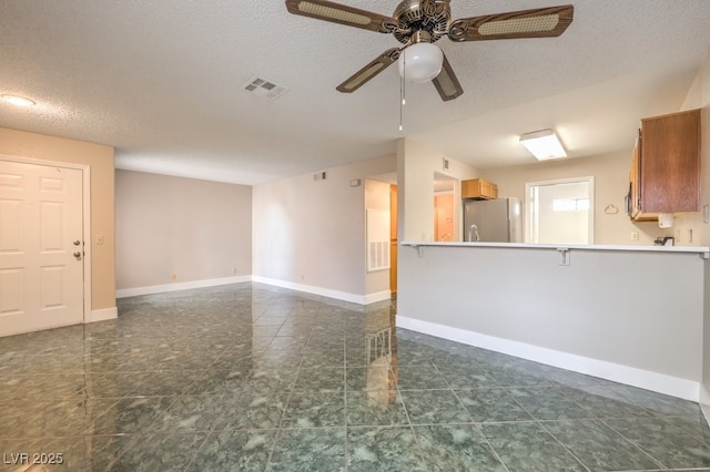 unfurnished living room featuring ceiling fan and a textured ceiling