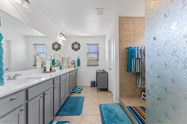 bathroom featuring tile patterned flooring, vanity, and tiled shower