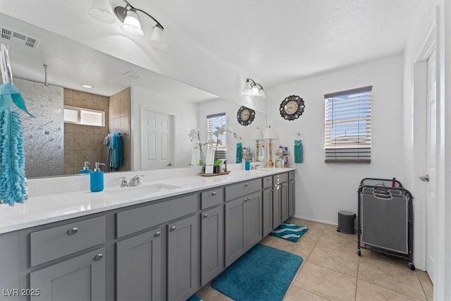 bathroom featuring tiled shower, vanity, and tile patterned flooring