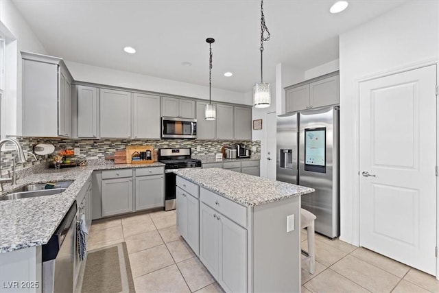 kitchen with sink, gray cabinets, appliances with stainless steel finishes, a kitchen island, and decorative light fixtures