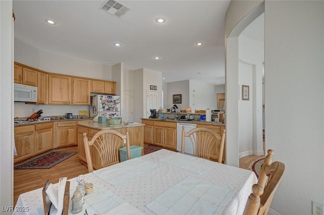 kitchen with a center island, sink, white appliances, and light hardwood / wood-style flooring