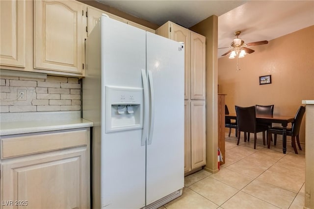 kitchen featuring light tile patterned flooring, white refrigerator with ice dispenser, backsplash, and ceiling fan