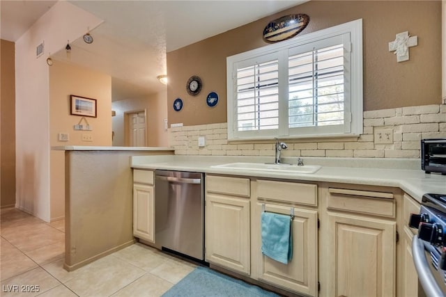 kitchen with sink, tasteful backsplash, light tile patterned floors, stainless steel appliances, and cream cabinets