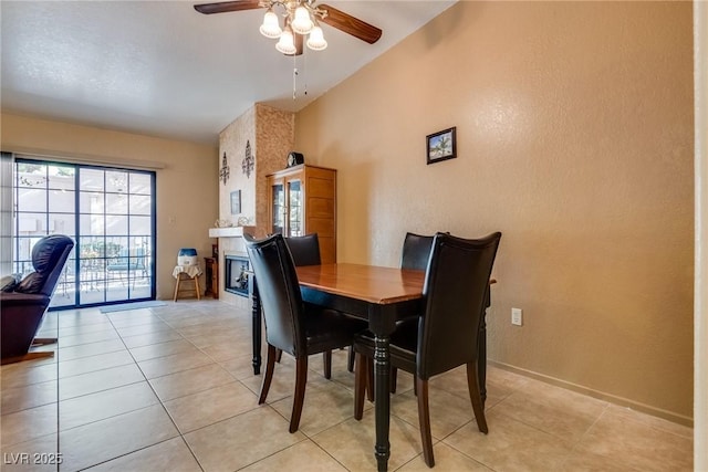 tiled dining space featuring a large fireplace and ceiling fan