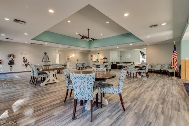 dining space with a raised ceiling and light hardwood / wood-style floors