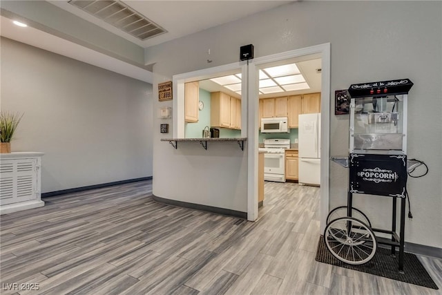 kitchen featuring white appliances, kitchen peninsula, and hardwood / wood-style flooring