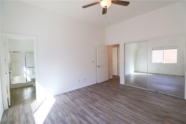 unfurnished bedroom with wood-type flooring, a closet, ceiling fan, and a high ceiling