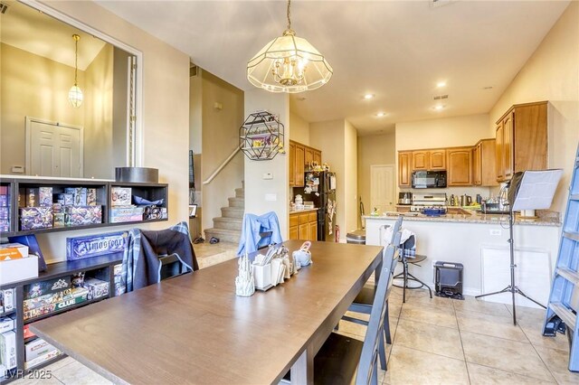 tiled dining space featuring a notable chandelier and a high ceiling