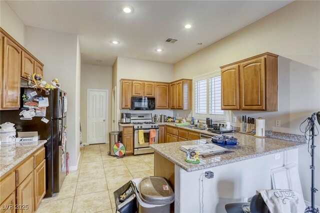 kitchen with light stone countertops, light tile patterned floors, black appliances, and kitchen peninsula