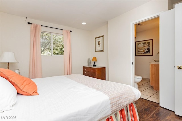 bedroom featuring connected bathroom and dark wood-type flooring