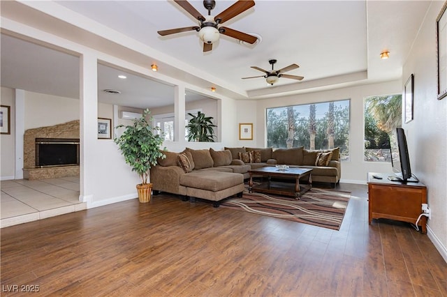 living room featuring a raised ceiling, a healthy amount of sunlight, and dark hardwood / wood-style flooring